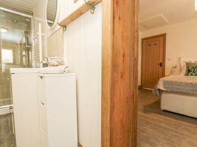 A small bathroom with a sink and towels next to a bedroom with a bed and a wooden door at The Lily Pad in Camborne