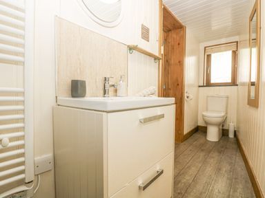 A bathroom with a white sink cabinet and a toilet near a window at The Lily Pad in Camborne