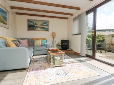A living room with a sectional sofa cushions coffee table and glass doors to a patio at The Lily Pad in Camborne