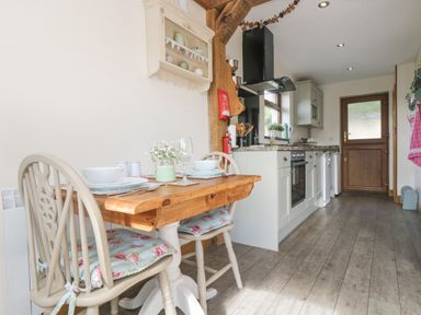 A kitchen with a wooden dining table set for two and white cabinets at The Lily Pad in Camborne