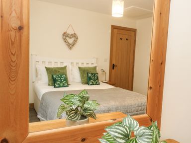 A bedroom with a bed green pillows and a heart-shaped wall decoration at The Lily Pad in Camborne