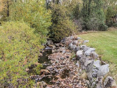 A stream surrounded by rocks and vegetation at Burnside House in Aviemore