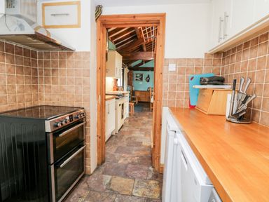 A kitchen with a stove countertop and knife set viewed through a wooden door frame at The Barn in Draycot Cerne near Malmesbury
