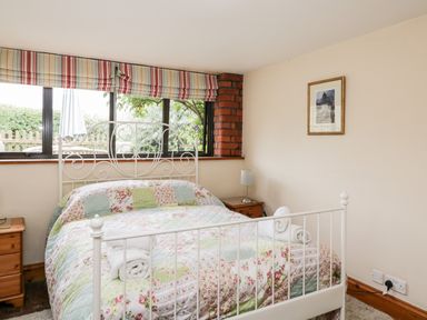 A bedroom with a white metal bed frame and patchwork quilt at The Barn in Draycot Cerne near Malmesbury