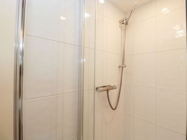 A tiled shower area with a handheld showerhead and glass door at The Barn in Draycot Cerne near Malmesbury