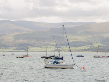A body of water with sailboats anchored and hills in the background at Seion Chapel in Beaumaris