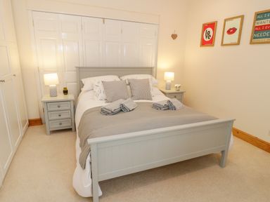 A bedroom with a bed two bedside tables with lamps and wall art at Seion Chapel in Beaumaris