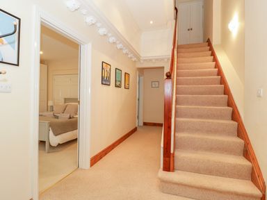 A hallway with carpeted stairs on the right and a bedroom visible through an open door on the left at Seion Chapel in Beaumaris