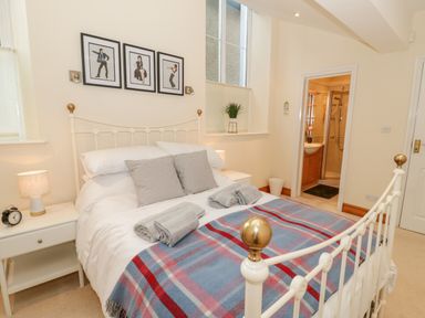 A bedroom with a white metal bed frame two bedside tables with lamps and an ensuite bathroom at Seion Chapel in Beaumaris