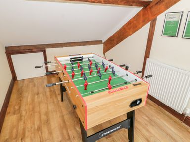 A room with a foosball table wooden floor radiator and framed pictures on wall at Seion Chapel in Beaumaris
