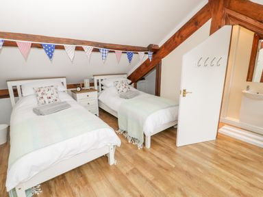 A bedroom with two single beds a nightstand and a partially open door leading to a bathroom at Seion Chapel in Beaumaris