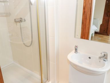 A bathroom with a shower enclosure and a sink with faucets at Seion Chapel in Beaumaris