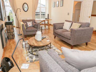 A living room with armchairs and a sofa around a wooden coffee table at Seion Chapel in Beaumaris