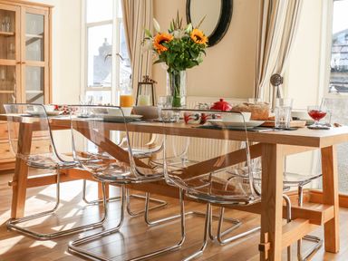 A dining room with a wooden table clear chairs a vase with flowers and tableware at Seion Chapel in Beaumaris