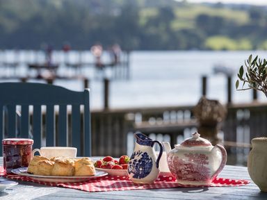 A table set with scones strawberries a jar of jam a cup a milk jug and a teapot by a lakeside waterhead cottage ecclerigg near troutbeck bridge