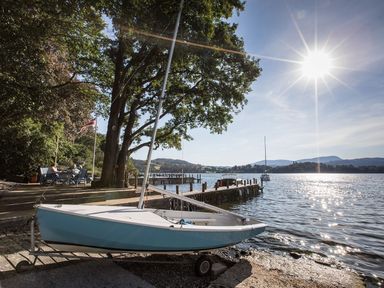 A small sailboat on a trailer near a tree and dock by a lake with hills in the background at Waterhead Cottage in Ecclerigg near Troutbeck Bridge