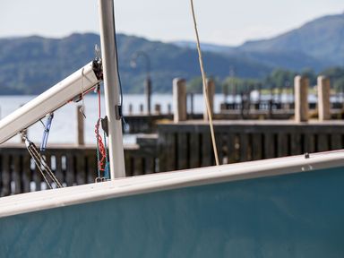 A close up of a boat mast and rigging with a dock and mountains in the background at Waterhead Cottage in Ecclerigg near Troutbeck Bridge