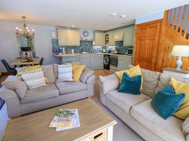 A living room with a sofa and kitchen area at Waterhead Cottage in Ecclerigg, near Troutbeck Bridge