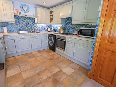 A kitchen with blue tiles and appliances at Waterhead Cottage in Ecclerigg, near Troutbeck Bridge
