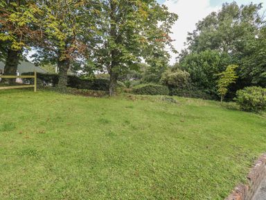 An outdoor garden area with grass trees and bushes at Hazel Cottage in Poughill near Bude