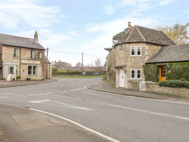 A street intersection with stone buildings including The Fox and Hounds pub at Pike Cottage in Acton Turville near Chipping Sodbury