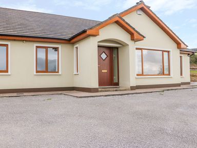 Front view of a single-story house with multiple windows and a wooden front door at Rossanean in Farranfore near Killarney County Kerry