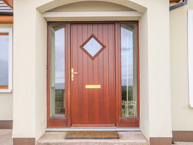 A wooden front door with glass panels on each side and a doormat at Rossanean Farranfore near Killarney County Kerry