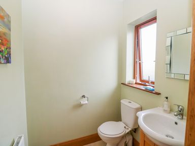 A bathroom with a toilet sink mirror and window at Rossanean Farranfore near Killarney County Kerry