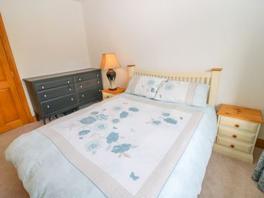 A bedroom with a bed a bedside table with a lamp and a dresser at Rossanean in Farranfore near Killarney County Kerry
