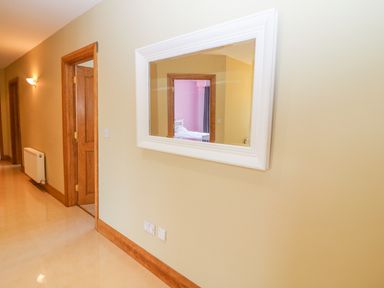 A hallway with beige walls wooden door frames a white framed mirror and a radiator at Rossanean in Farranfore near Killarney County Kerry