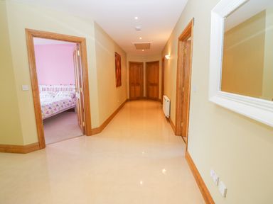 A hallway with tiled floor and wooden doors leading to a room with a bed at Rossanean in Farranfore near Killarney County Kerry