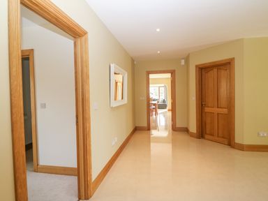 A hallway with beige walls wooden door frames and a mirror leading to a room with a dining table and chairs at Rossanean in Farranfore near Killarney County Kerry