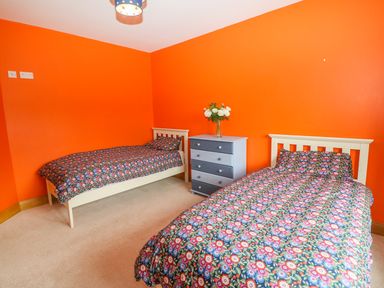 A bedroom with two single beds a chest of drawers and orange walls at Rossanean in Farranfore near Killarney County Kerry
