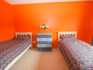 A bedroom with two single beds with floral bedding and a blue chest of drawers with flowers on top at Rossanean in Farranfore near Killarney County Kerry