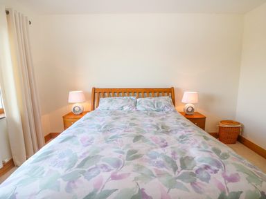 A bedroom with a wooden bed and floral bedding with two bedside tables and lamps at Rossanean in Farranfore near Killarney County Kerry