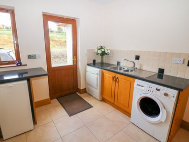 A utility room with a washing machine dryer sink and a door at Rossanean in Farranfore near Killarney County Kerry