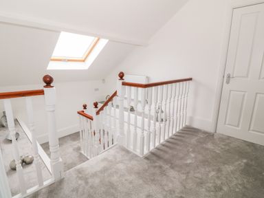 A staircase with white railing and wooden handrail under a skylight at Lyngaran House in Holyhead