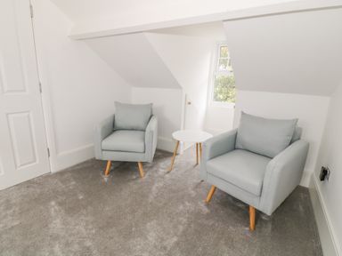 A room with two gray armchairs and a small round white table at Lyngaran House in Holyhead