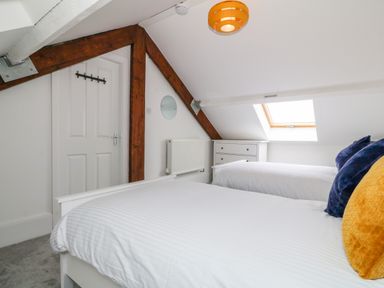 A bedroom with two single beds a chest of drawers and a skylight window at Lyngaran House in Holyhead