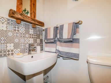 A bathroom sink with soap and towels hanging on a towel rack above a toilet at Blue Bay Beach House in Mawgan Porth