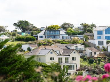 A view of houses on a hillside with greenery and trees at Blue Bay Beach House in Mawgan Porth