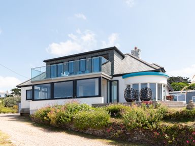 A house with balcony chairs and garden flowers at Blue Bay Beach House in Mawgan Porth
