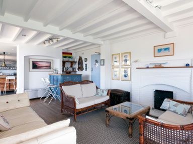 A living room with sofas coffee table fireplace and bar area at Blue Bay Beach House in Mawgan Porth