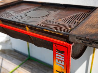 A close up of a grill with a red metal frame and a wooden side table at Blue Bay Beach House in Mawgan Porth