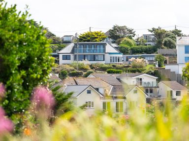 Houses with balconies and gardens surrounded by trees and plants at Blue Bay Beach House in Mawgan Porth
