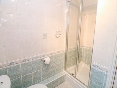 A bathroom with a corner shower enclosure tiled walls and a toilet at Lambkin Cottage in St Columb Major