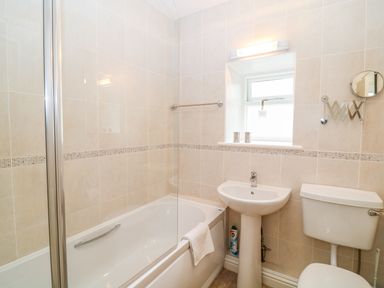A bathroom with a bathtub shower sink toilet and tiled walls at Cornflower Cottage in St Columb Major