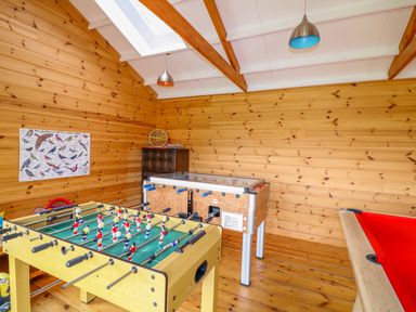 A game room with a foosball table a pool table and a poster of birds at Cornflower Cottage in St Columb Major