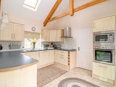 A kitchen with light wood cabinets a black countertop a skylight and exposed wooden beams at Forget-me-not in St Columb Major