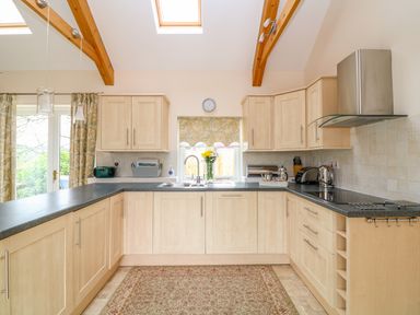 A kitchen with wooden cabinets black countertops a stove sink flowers and skylights at Forget-me-not in St Columb Major